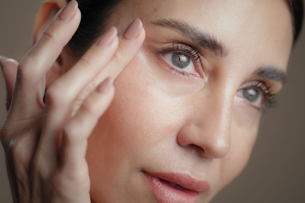 Close-up of woman touching skin near eye.