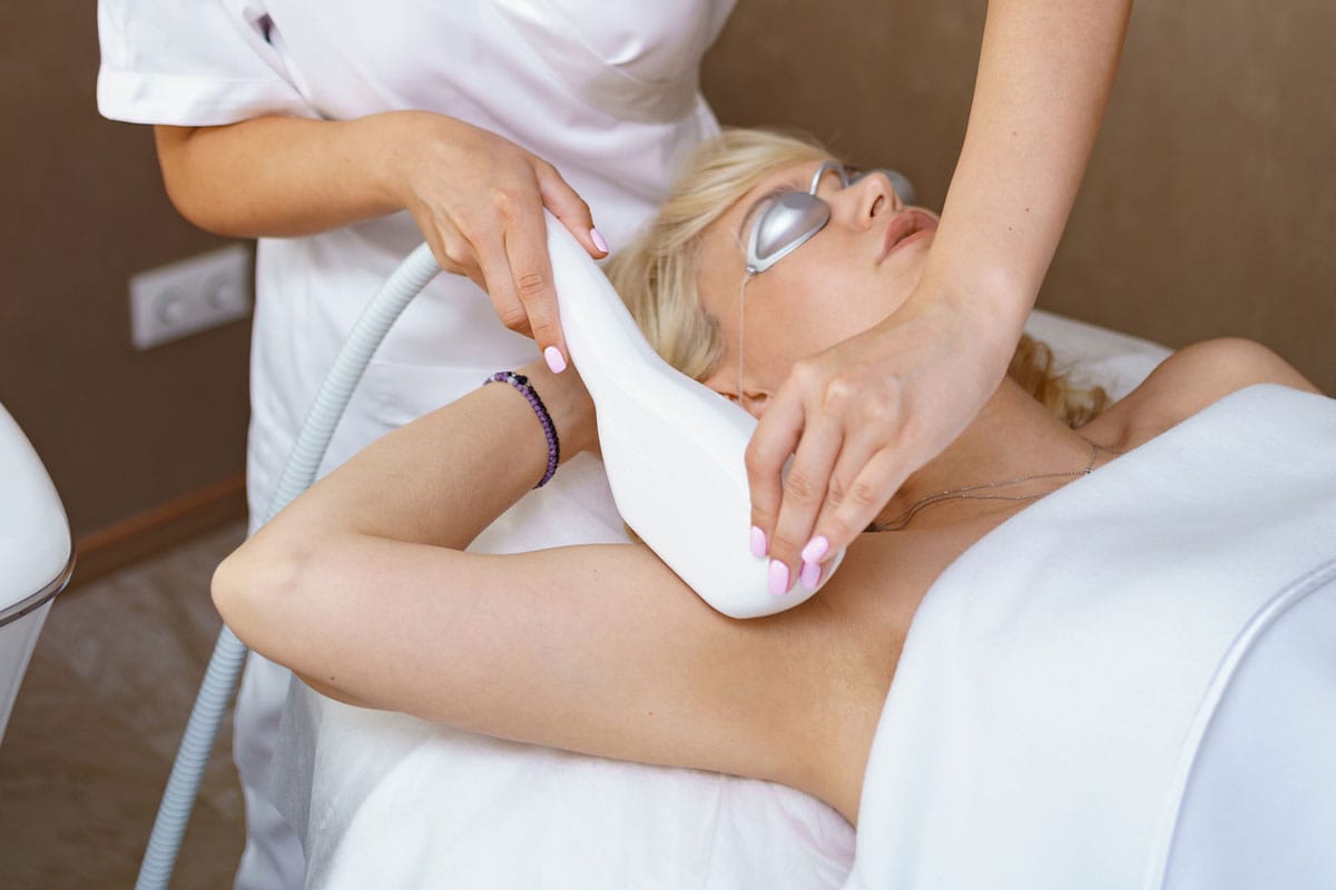 Woman receiving laser hair removal on underarm.