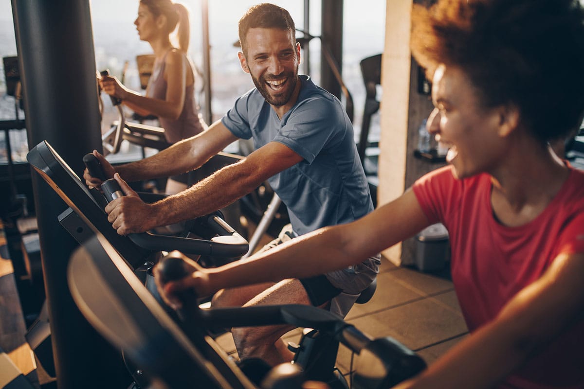 People on exercise bikes looking happy and healthy
